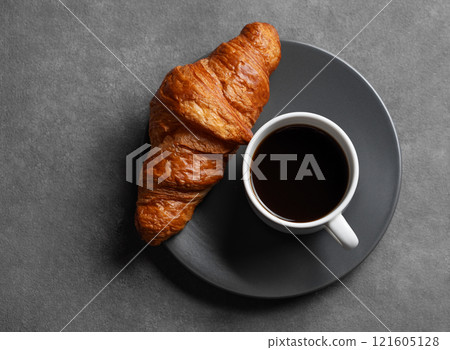 Cup of espresso coffee and fresh croissant on grey plate on dark background. 121605128
