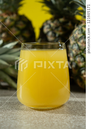 Pineapple juice in a glass among fresh pineapple fruit close-up. 121605171