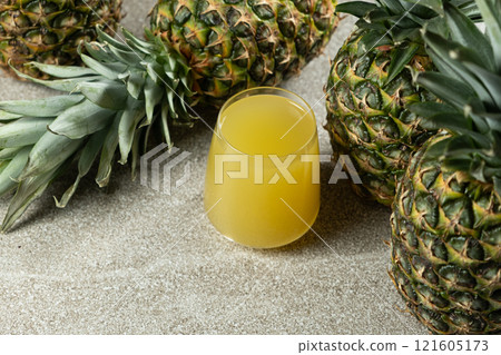 Pineapple juice in a glass among fresh pineapple fruit close-up. 121605173