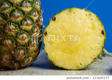 Slice of pineapple and whole pineapple on blue background close-up. 121605177