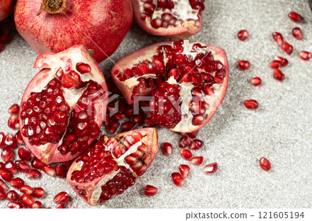 Pomegranate Seeds and Pomegranates on a Stone Gray Background Close-up Pomegranate Seeds and Pomegranates on a Stone Gray Background Close-up 121605194