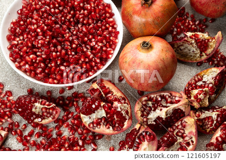 Pomegranate seeds in a plate and lots of whole and peeled pomegranates. Pomegranate seeds in a plate and lots of whole and peeled pomegranates. 121605197