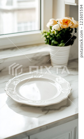 Minimalist serving plate on marble countertop with flowers and natural light 121605594