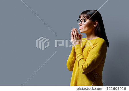 Profile view, serious female with hands folded on gray studio background 121605926