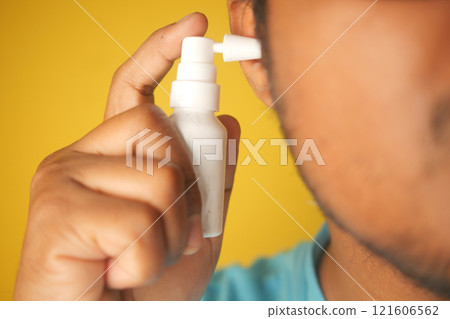 Close up of men using spray to remove earwax Close up of men using spray to remove earwax 121606562