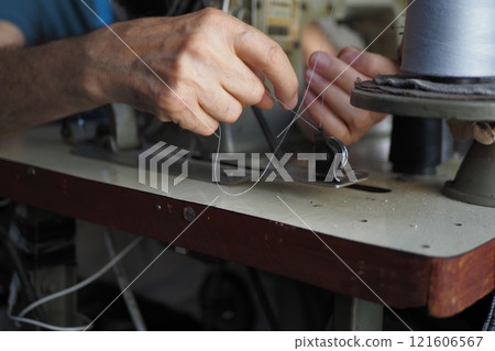 A closeup view of hands skillfully using a sewing machine for tailoring A closeup view of hands skillfully using a sewing machine for tailoring 121606567