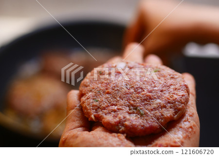 Freshly prepared, cooked burger patty held in hand, ready to enjoy Freshly prepared, cooked burger patty held in hand, ready to enjoy 121606720