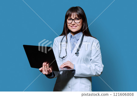 Portrait of female doctor with laptop on blue background Portrait of female doctor with laptop on blue background 121606808