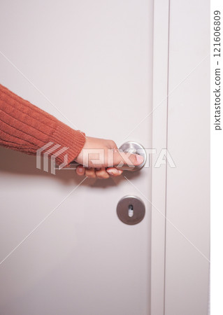 A Hand Reaching Out to Grasp the Door Knob in Order to Open a Door A Hand Reaching Out to Grasp the Door Knob in Order to Open a Door 121606809