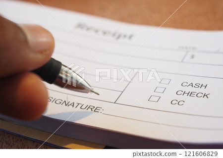 Signing the Receipt by Hand Using a Pen on the Payment Form Provided Signing the Receipt by Hand Using a Pen on the Payment Form Provided 121606829
