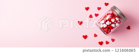 Glass jar full of heart shaped confetti on pink background. Valentines background. Love banner 121606865