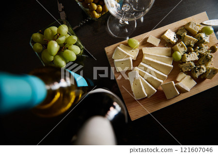 Cheese platter served with green grapes and wine on a wooden board 121607046