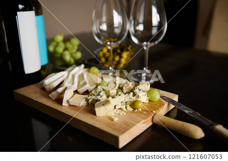 Assorted Cheese Platter with Grapes and Wine on a Wooden Board 121607053