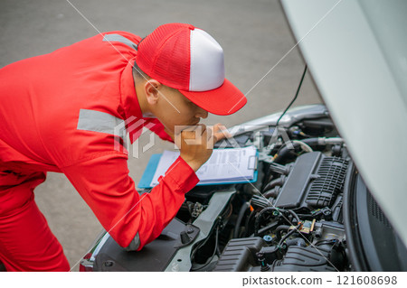 Automobile Mechanic Inspecting Engine with Service Report on Clipboard Automobile Mechanic Inspecting Engine with Service Report on Clipboard 121608698