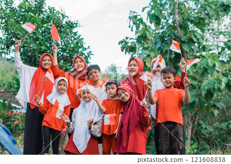 young girls in headscarves and smiling boys holding small Indonesian flags 121608838