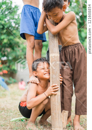 a child squats on a friend's step as a fulcrum 121608854