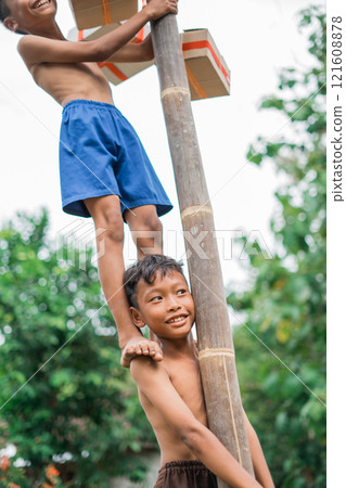 a boy laughs easily when a friend stands on his shoulder 121608878