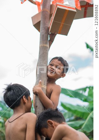 laughing children climbing to reach the hanging prize while holding 121608892