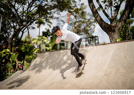 A Skateboarder Skillfully Performing Various Tricks in an Urban Skate Park A Skateboarder Skillfully Performing Various Tricks in an Urban Skate Park 121608917