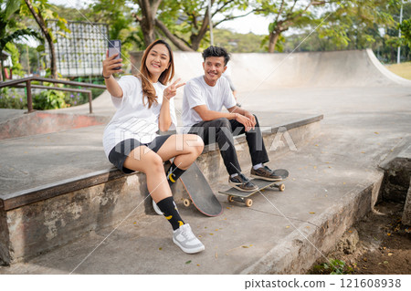 A Group of Friends Enjoying a Fun Selfie Session at a Skatepark on a Bright Sunny Day 121608938