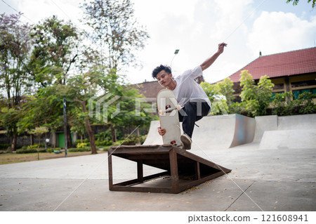 Skateboarder Excitingly Performing Tricks at a Local Skate Park Environment 121608941