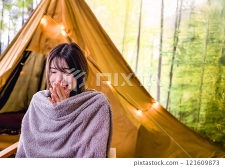 It's cold and a young woman wrapped in a blanket Camping image 121609873