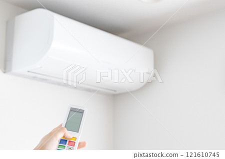 A woman's left hand operating an air conditioner remote control A woman's left hand operating an air conditioner remote control 121610745