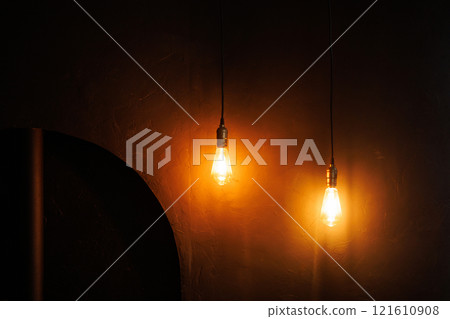 Two dark-light bulbs on a long cord are twined from the ceiling 121610908