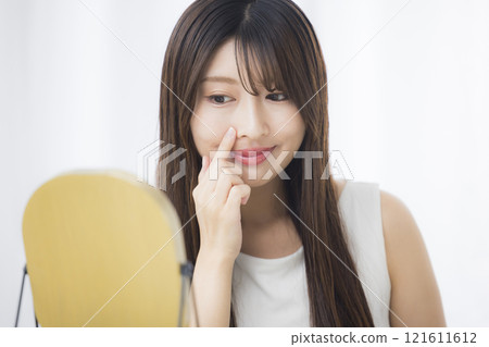 一位年輕女子照鏡子，擔心自己的皮膚 121611612
