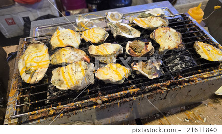 street vendor uses a torch flame to prepare delicious grilled oyster with flair and skill, showcasing the vibrant atmosphere of bustling night Thai markets street vendor uses a torch flame to prepare delicious grilled oyster with flair and skill, showcasing the vibrant atmosphere of bustling night Thai markets 121611840