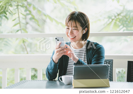 Woman on terrace with digital gadget Woman on terrace with digital gadget 121612047