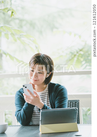 Woman on terrace with digital gadget 121612050