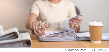 Asian woman reading financial report, female businesswoman sign contract or writing documents paper at home or office late night. Overworked, work hard and business concept Asian woman reading financial report, female businesswoman sign contract or writing documents paper at home or office late night. Overworked, work hard and business concept 121612517