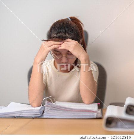 Asian woman having Tired and Stressed while working, female businesswoman having headache and Migraine at office, Exhausted woman with document folder stack at home late night. Overworked and Overtime Asian woman having Tired and Stressed while working, female businesswoman having headache and Migraine at office, Exhausted woman with document folder stack at home late night. Overworked and Overtime 121612519