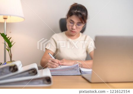 Asian woman working with computer laptop, female businesswoman reading report and sign contract with documents folder stack at home or office late night. Overworked, work hard and business concept Asian woman working with computer laptop, female businesswoman reading report and sign contract with documents folder stack at home or office late night. Overworked, work hard and business concept 121612554