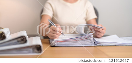 Asian woman reading financial report, female businesswoman sign contract or writing documents paper at home or office late night. Overworked, work hard and business concept Asian woman reading financial report, female businesswoman sign contract or writing documents paper at home or office late night. Overworked, work hard and business concept 121612627