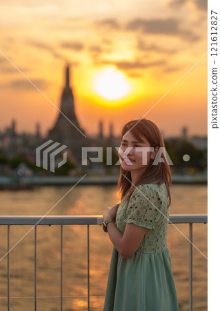 tourist woman enjoys view to Wat Arun Temple in sunset, Traveler visits Temple of Dawn near Chao Phraya river from rooftop bar. Landmark and Travel destination in Bangkok, Thailand and Southeast Asia 121612827