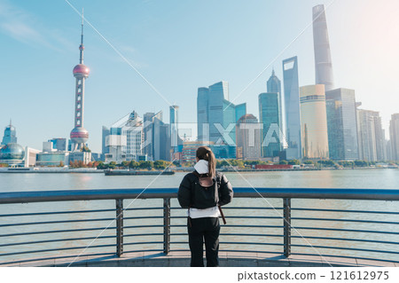 woman traveler visiting in Shanghai, China. Female Tourist with backpack sightseeing Shanghai view of Lujiazui in The Bund of Shanghai. landmark and popular for tourism attractions. Vacation concept 121612975