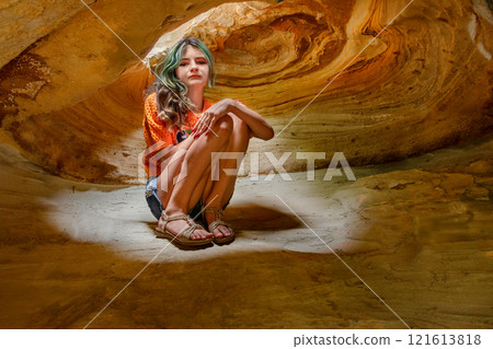 Teen girl inside of dark cave with light beam. 121613818