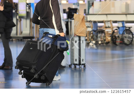 一名旅客在機場拉著行李箱 一名旅客將行李裝入手推車並移動 121615457