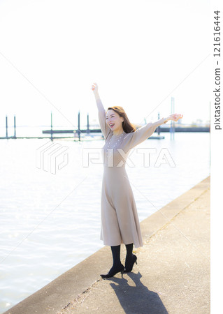 A beautiful lady standing by the water under a clear autumn sky. A beautiful lady standing by the water under a clear autumn sky. 121616444