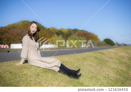 A beautiful lady standing by the water under a clear autumn sky. A beautiful lady standing by the water under a clear autumn sky. 121616458