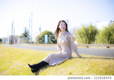 A beautiful lady standing by the water under a clear autumn sky. A beautiful lady standing by the water under a clear autumn sky. 121616459