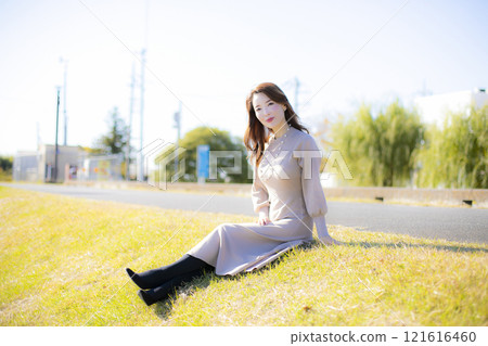 A beautiful lady standing by the water under a clear autumn sky. 121616460