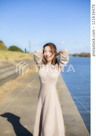 A beautiful lady standing by the water under a clear autumn sky. A beautiful lady standing by the water under a clear autumn sky. 121616478