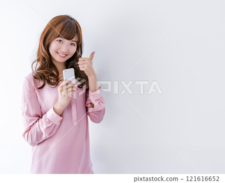 一位年輕女子手裡拿著手機給了一個好兆頭 121616652