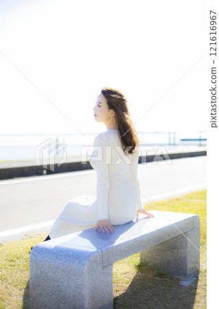 A beautiful lady standing by the water under a clear autumn sky. A beautiful lady standing by the water under a clear autumn sky. 121616967