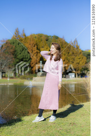 A beautiful lady standing by the water under a clear autumn sky. A beautiful lady standing by the water under a clear autumn sky. 121616990