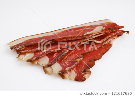 Cured slices of pork meat is arranged neatly with visible marbling, showcasing rich texture 121617680