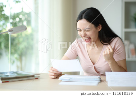 Excited asian woman celebrating end of payment holding receipt Excited asian woman celebrating end of payment holding receipt 121618159